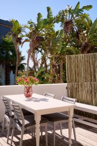 a white table and chairs on a deck with palm trees at ocean10 Guesthouse in Cape Town