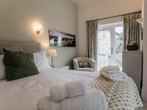 a bedroom with a white bed with a chair and a window at 3 Bed in Bedale oc-g0095 in Crakehall