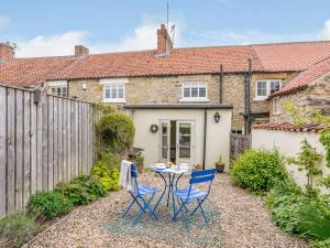 a small garden with a table and chairs in front of a cottage at 3 Bed in Helmsley oc-82891 in Helmsley