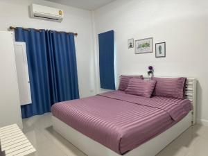 a bedroom with a bed with purple sheets and blue curtains at Baanpeanutsvilla Huahin in Hua Hin +33 photos