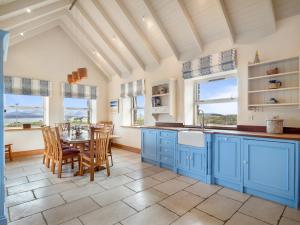 a kitchen with blue cabinets and a table and chairs at Diamond Cottage in Ballyconneely