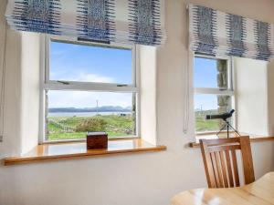two windows with blue roman blinds in a dining room at Diamond Cottage in Ballyconneely