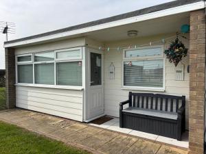 a bench sitting outside of a house with a window at 179, Two bed chalet on Sund0wner Holiday Park - Sleeps 4, free WiFi, sorry no pets - entertainment options close by in Hemsby