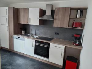 a kitchen with white cabinets and a stove top oven at Ferienwohnung "Kleiner" EIFELTRAUM in Mettendorf +3 photos