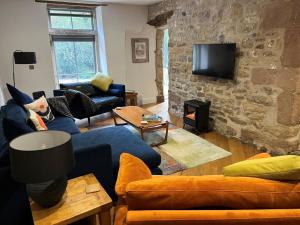 a living room with a blue couch and a stone wall at 3 Bed in Skipton oc-84014 in Rylstone