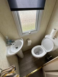 a bathroom with a toilet and a sink and a window at Luxury Caravan Coastfields Holiday Village in Ingoldmells +9 photos