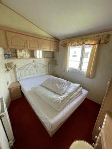 a large bed in a small room with a window at Luxury Caravan Coastfields Holiday Village in Ingoldmells