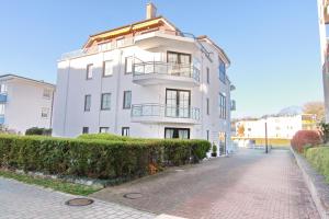 a white building on a street next to a sidewalk at Haus Titania App 6 inkl WLAN in Grömitz