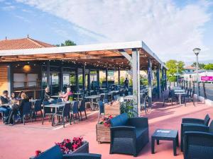 a patio with people sitting at tables and chairs at Mobilhome L'Instant Vacances - La Plage in Mimizan-Plage