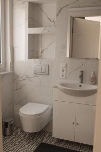a white bathroom with a toilet and a sink at Haus Auf Bulz - Klippeneck in Denkingen +47 photos