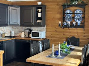 a kitchen with black cabinets and a wooden table with candles at Grønebakkins smørøye in Beitostøl