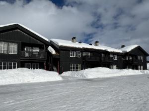 a black building with snow piled up in front of it at Grønebakkins smørøye in Beitostøl