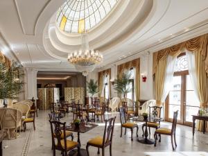 a dining room with tables and chairs and a chandelier at Grecotel Larissa Imperial in Larisa