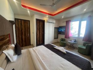 a bedroom with a large bed with two green chairs at V Hotel Dev Residency Airport Pick up complimentary in New Delhi
