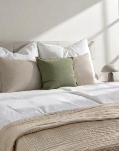 a bed with white sheets and green pillows at Suites am Herzogberg in Brunn am Gebirge