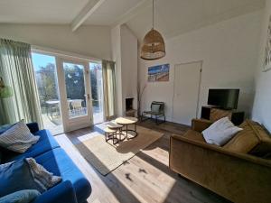 a living room with a blue couch and a tv at Bungalow 024 in Petten