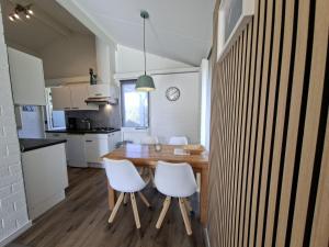 a kitchen and dining room with a wooden table and white chairs at Bungalow 024 in Petten +8 photos
