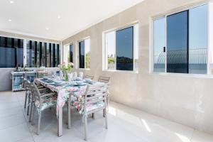 a dining room with a table and chairs and windows at Sea View Luxury Penthouse in Ballito