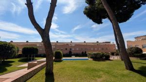 a building with a pool and two palm trees at EVH114 Casa con piscina comunitaria in Altafulla