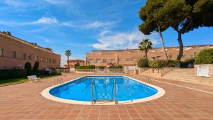 a swimming pool in a courtyard with trees and buildings at EVH114 Casa con piscina comunitaria in Altafulla