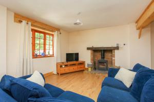 a living room with a blue couch and a fireplace at Dulcie's Cottage in Wootton