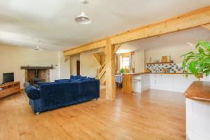 a living room with a blue couch and a kitchen at Dulcie's Cottage in Wootton