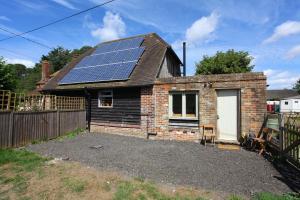 a small brick house with solar panels on the roof at Dulcie's Cottage in Wootton