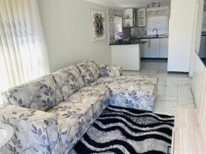 a living room with a couch and a kitchen at Obaa Sima Guest House in Mthatha