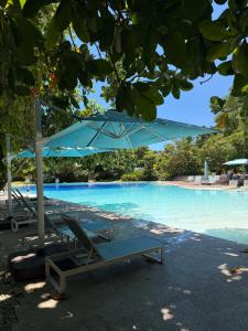 a lounge chair and umbrella next to a swimming pool at Relaxing 1-Bedroom Resort Condo Unit at Tambuli Seaside Living, Mactan, Lapu-lapu City in Maribago