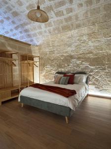 a bedroom with a bed and a stone wall at Dimora Antica Santa Chiara in Trani