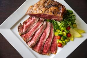 a plate of meat and bread and vegetables on a table at Hotel Green Plaza Hakuba in Otari