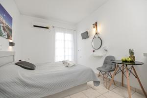 a white bedroom with a bed and a table at Naxos Diol in Naxos Chora