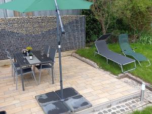 a patio with a table and chairs and an umbrella at Ferienwohnung "Kleiner" EIFELTRAUM in Mettendorf