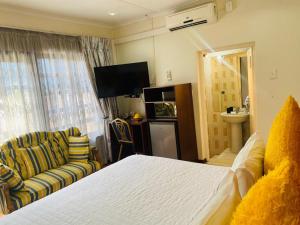 a bedroom with a bed and a couch and a television at Obaa Sima Guest House in Mthatha