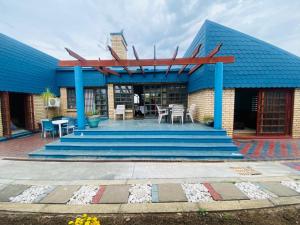 a building with a blue roof with tables and chairs at Obaa Sima Guest House in Mthatha