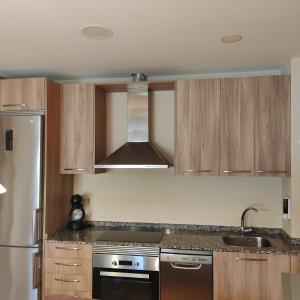 a kitchen with wooden cabinets and a stainless steel appliance at Malpica I in Malpica