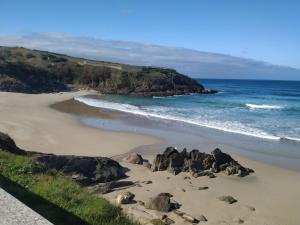 a beach with rocks in the sand and the ocean at Malpica I in Malpica +8 photos