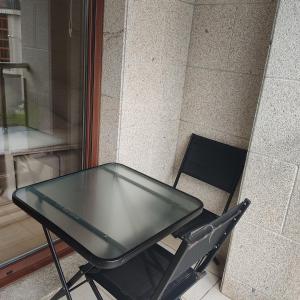 a glass table and a chair next to a wall at Malpica I in Malpica