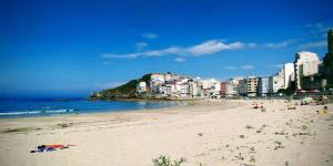 a beach with people on the sand and buildings at Malpica I in Malpica