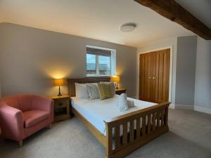 a bedroom with a bed and a chair and a window at Welcome To Wrexham - Hot Tub Luxury 5 bed House in Holt