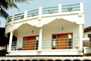 a white house with a balcony on top of it at Heather Home Stay in Cochin