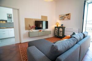 a living room with a blue couch and a tv at Open Space Suite in the Center of Salerno, modern apartment into Historic District, 250 meters from seafront and 20 meters from the Main Street Corso Garibaldi in Salerno