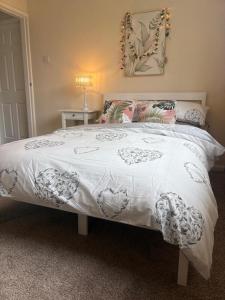 a bed with a white comforter and pillows on it at Westfields Bungalow in Mirfield