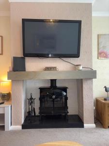 a living room with a fireplace with a flat screen tv on top at Westfields Bungalow in Mirfield