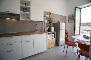 a kitchen with white cabinets and a white refrigerator at Open Space Suite in the Center of Salerno, modern apartment into Historic District, 250 meters from seafront and 20 meters from the Main Street Corso Garibaldi in Salerno
