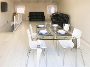 a dining room with a glass table and white chairs at Budello di Alassio, ampio appartamento con box vicino al mare in Alassio