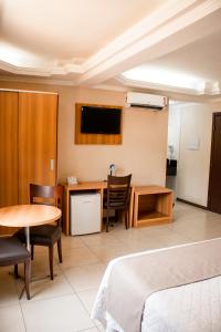 a hotel room with a bed and a table and a desk at Hotel Dom Otto in Vespasiano