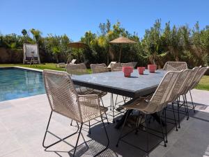 a patio table with chairs and a pool at Villa LaLa in Marrakesh +4 photos