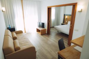 a living room with a couch and a bedroom at Hotel Bonalba Alicante in El Campello