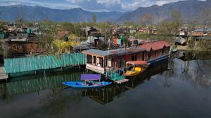 a boat is docked next to a village on the water at H.B.victoria Garden in Srinagar